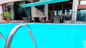 A swimming pool with a metal ladder, outdoor seating area, and potted plants. - Andza Tbilisi Hotel (Tbilisi)