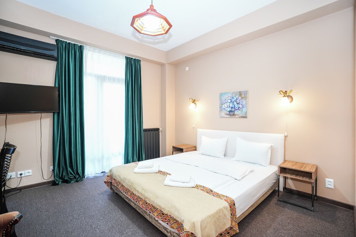 Habitació d'hotel amb un llit gran, una televisió de pantalla plana, un escriptori i una cadira.