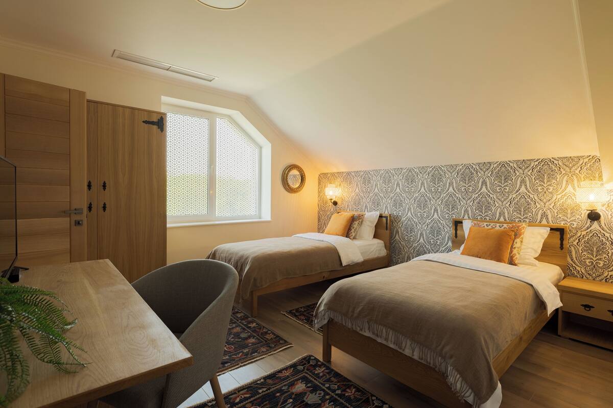 A bedroom with two single beds, a desk, and a chair.
