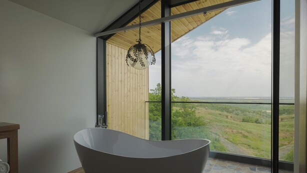 A modern bathroom with a freestanding bathtub, large windows, and a view of a green landscape. - Purcari Retreat (Purcari)
