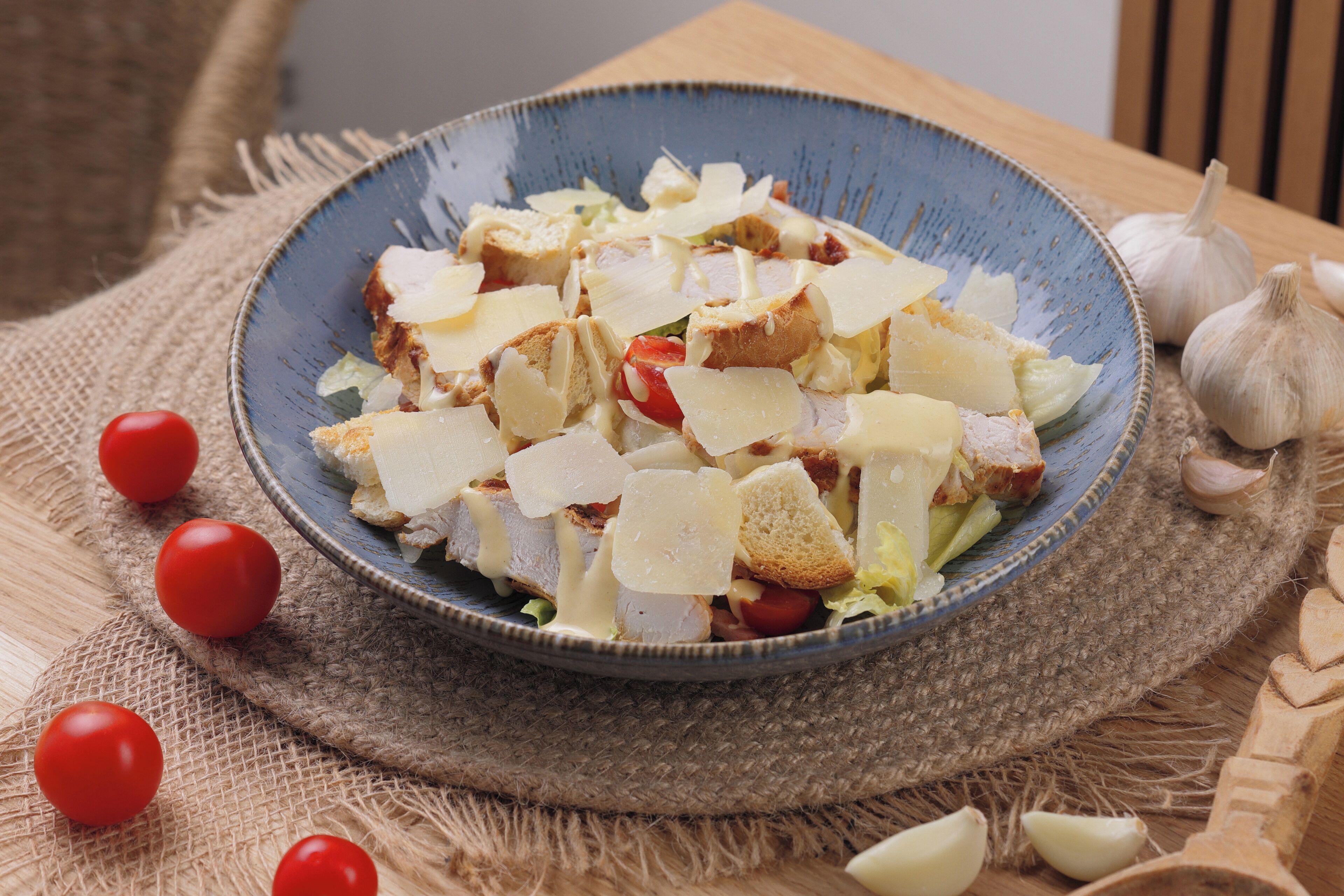 Ensalada con tomates, queso y pan sobre una mesa rústica.