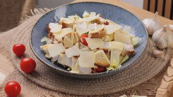 Ensalada con tomates, queso y pan sobre una mesa rústica.