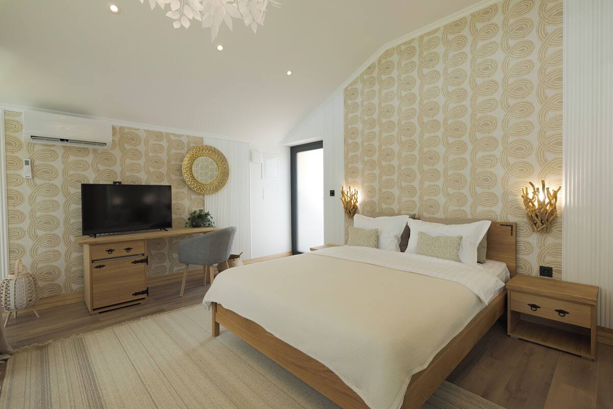 A bedroom with a large bed, a desk, a TV, and a chair.