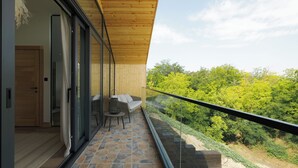 A balcony with stone flooring, a wooden ceiling, and a glass door leading to a room. - Purcari Retreat (Purcari)
