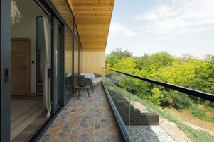 A balcony with stone flooring, a wooden ceiling, and a glass door leading to a room.