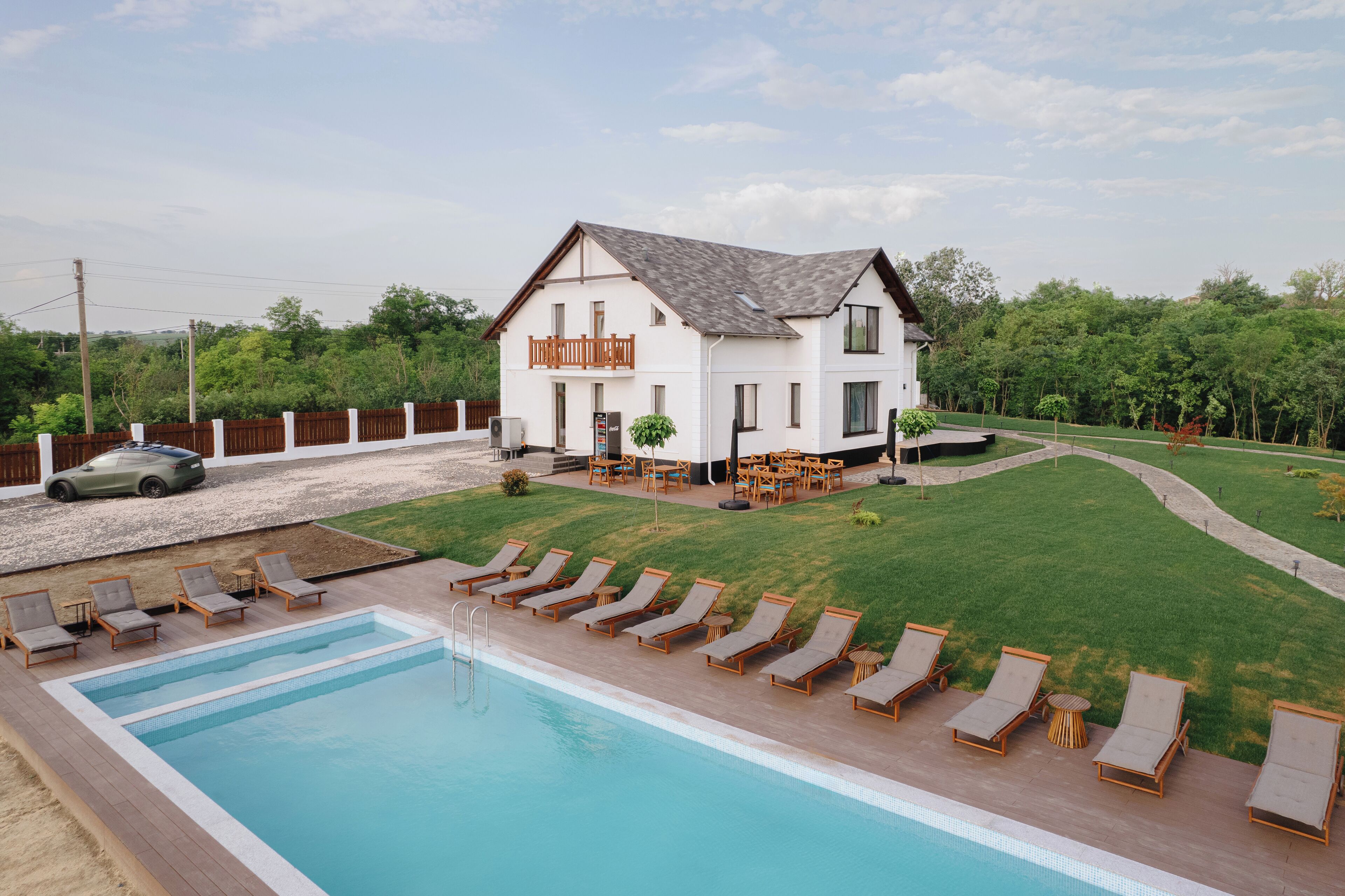 A two-story house with a swimming pool, outdoor seating, and a fenced yard.