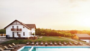 A large white building with a balcony, a swimming pool with lounge chairs, and a well-maintained lawn. - Purcari Retreat (Purcari)