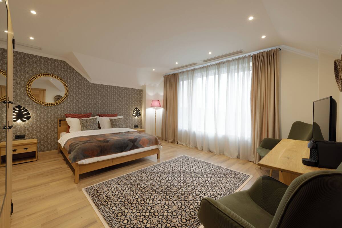 A modern bedroom with a bed, bedside tables, a desk, and a chair.