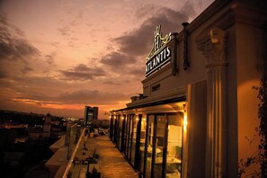A hotel named 'Atlantis' with a rooftop terrace featuring a glass balustrade and a view of the cityscape during sunset. -  Atlantis Alger Air De France (Algiers)