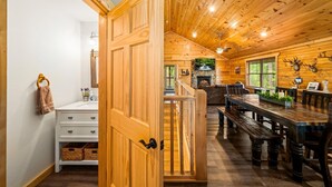 L’intérieur d’un chalet en bois comprend un coin repas, une cheminée et offre une vue sur l’extérieur.