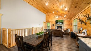 L’intérieur d’un chalet en bois comprend un coin repas, une cheminée et des décorations représentant des têtes de cerf.
