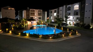 Un hotel con piscina circondata da lettini e ombrelloni, con diversi edifici sullo sfondo.