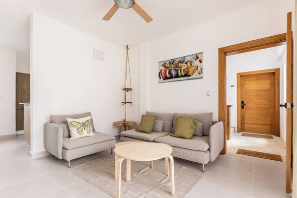 A modern living room with two sofas, a coffee table, a painting on the wall, and a wooden door.