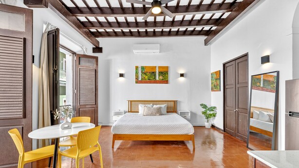 Une chambre à coucher avec un lit, une table à manger avec des chaises et un ventilateur de plafond.
