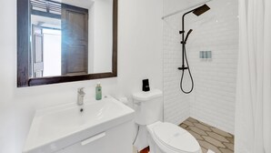 Une salle de bain moderne avec un lavabo, des toilettes et une douche, le tout de couleur blanche.