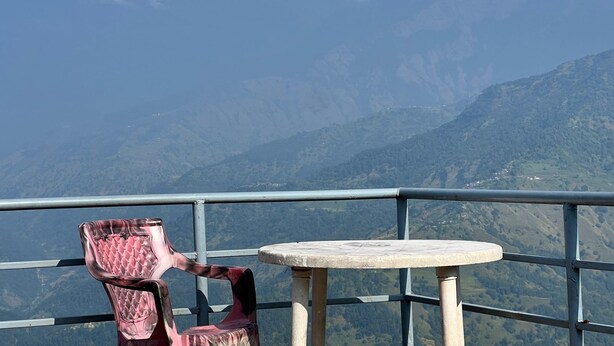 A chair and a small table on a balcony with a mountain view. - Pari Ghar Guest House (Gilung)