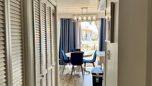A hallway with a dining area featuring a table and chairs, a ceiling fan, and a view of the outside. - Beach + Golf Included Stay, Sandpiper 1003! (destin)