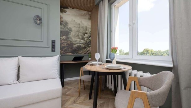 A dining area with a round table, chairs, a sofa, and a mural on the wall.