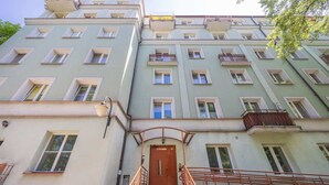 A multi-story building with a central entrance, balconies, and a staircase leading to the entrance.