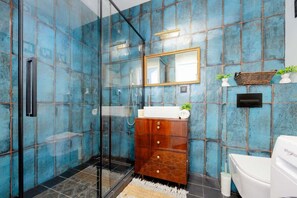 Un baño moderno con cabina de ducha de vidrio, tocador de madera con espejo y un inodoro blanco.