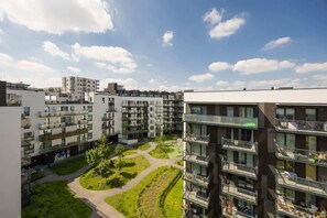 A modern apartment complex with multiple buildings, a central courtyard with greenery, and balconies on each floor.