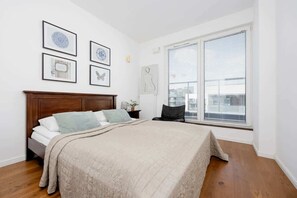 Un dormitorio con una cama grande, cabecera de madera, ventana con persianas y cuadros en la pared.