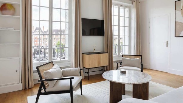 A modern living room with a sofa, a round coffee table, and a TV mounted on the wall. - A Splendide 1-BR au Quai des Orfèvres (Paris)