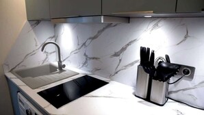 A kitchen with a double sink, a built-in stove, and a knife block. - A Splendide 1-BR au Quai des Orfèvres (Paris)