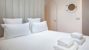 Una habitación de hotel con una cama grande, dos almohadas, un espejo redondo y una puerta.