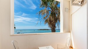 Un balcón con vistas despejadas al mar, una palmera y dos sillas cómodas.
