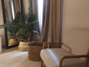 Relax in a serene space with a single chair, large mirror, and lush greenery.