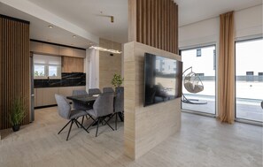 Una cocina moderna con comedor, un televisor grande y una silla colgante junto a la ventana.