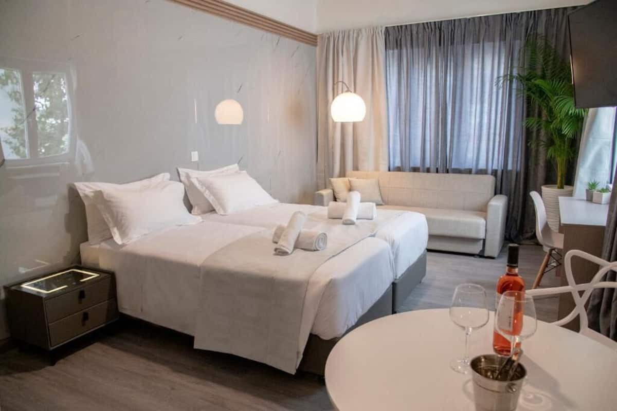 Une chambre d’hôtel avec deux lits, un canapé, une table à manger et un téléviseur.