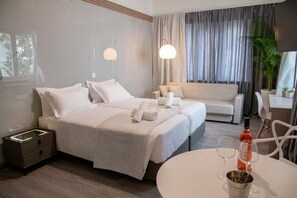 A hotel room with two beds, a sofa, a dining table, and a TV. - Celia Residence (Alimos)