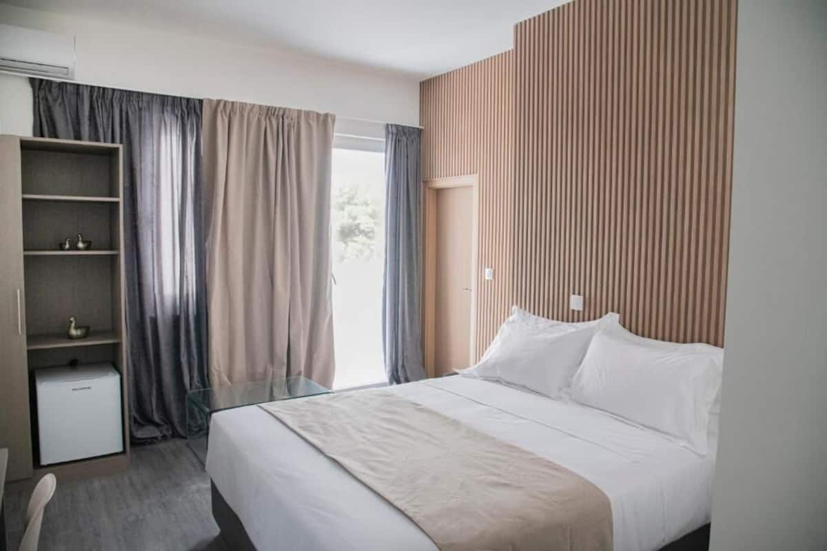 Une chambre d’hôtel moderne dotée d’un grand lit, d’un bureau en verre, d’une armoire et offrant une vue sur l’extérieur.