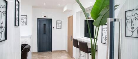 A hallway with a marble floor, a door, and framed artwork on the walls.