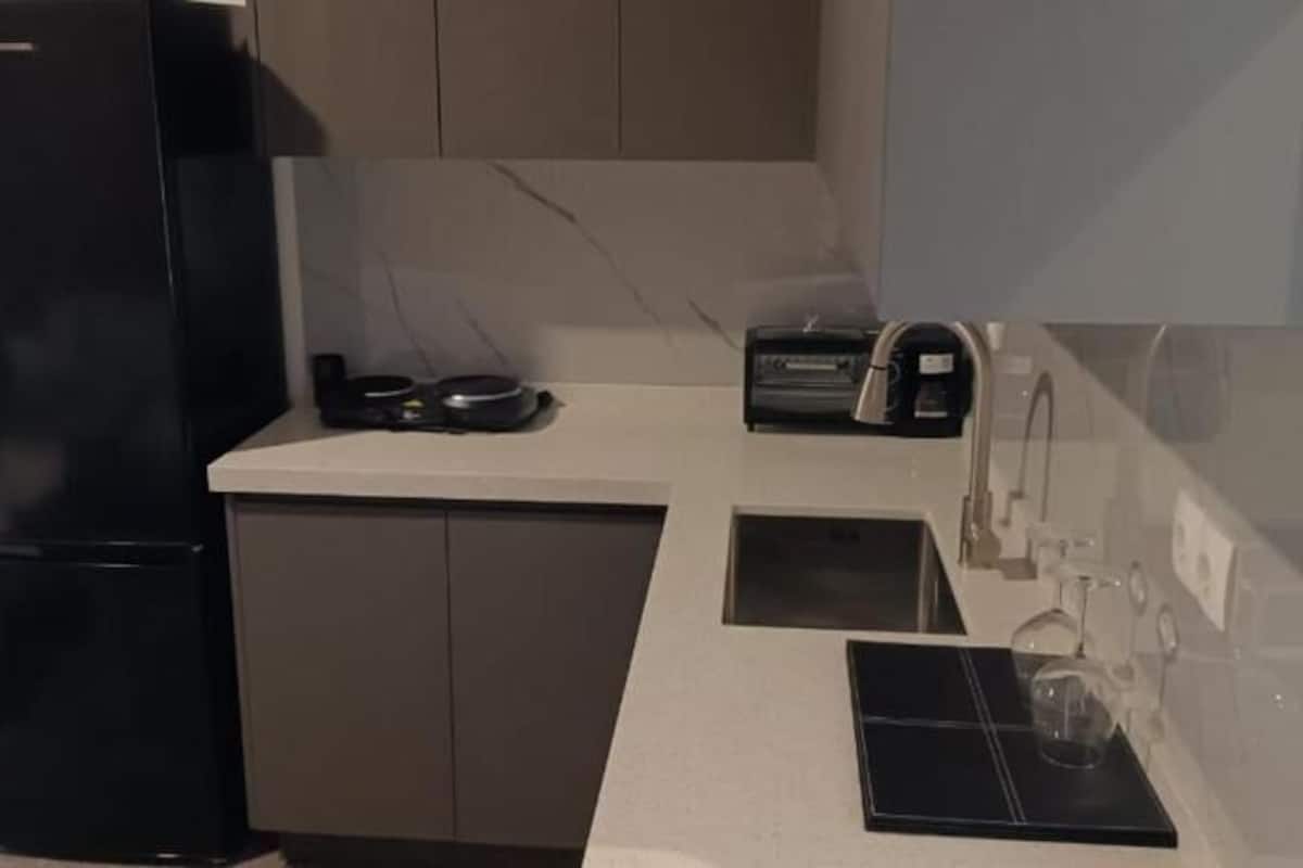 Une cuisine compacte équipée d’un réfrigérateur, d’une machine à café et d’un évier.