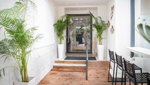 A modern hotel lobby with a wooden floor, potted plants, and a seating area with black chairs. - Celia Residence (Alimos)