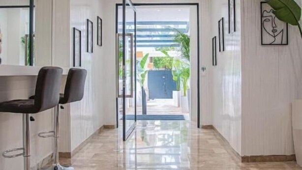 A modern hotel corridor with a glass door leading to a garden area. - Celia Residence (Alimos)