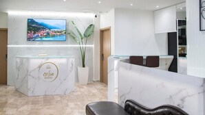 A reception area with a marble counter, a television mounted above it, and a potted plant. - Celia Residence (Alimos)