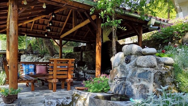 A rustic outdoor seating area with wooden benches and a stone fountain. - Villa Markiza - Summer House by the River, at the National Park Central Balkan   (Kalofer)