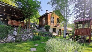 A rustic wooden house with a stone pathway leading to the entrance, surrounded by lush greenery and a small garden. - Villa Markiza - Summer House by the River, at the National Park Central Balkan   (Kalofer)