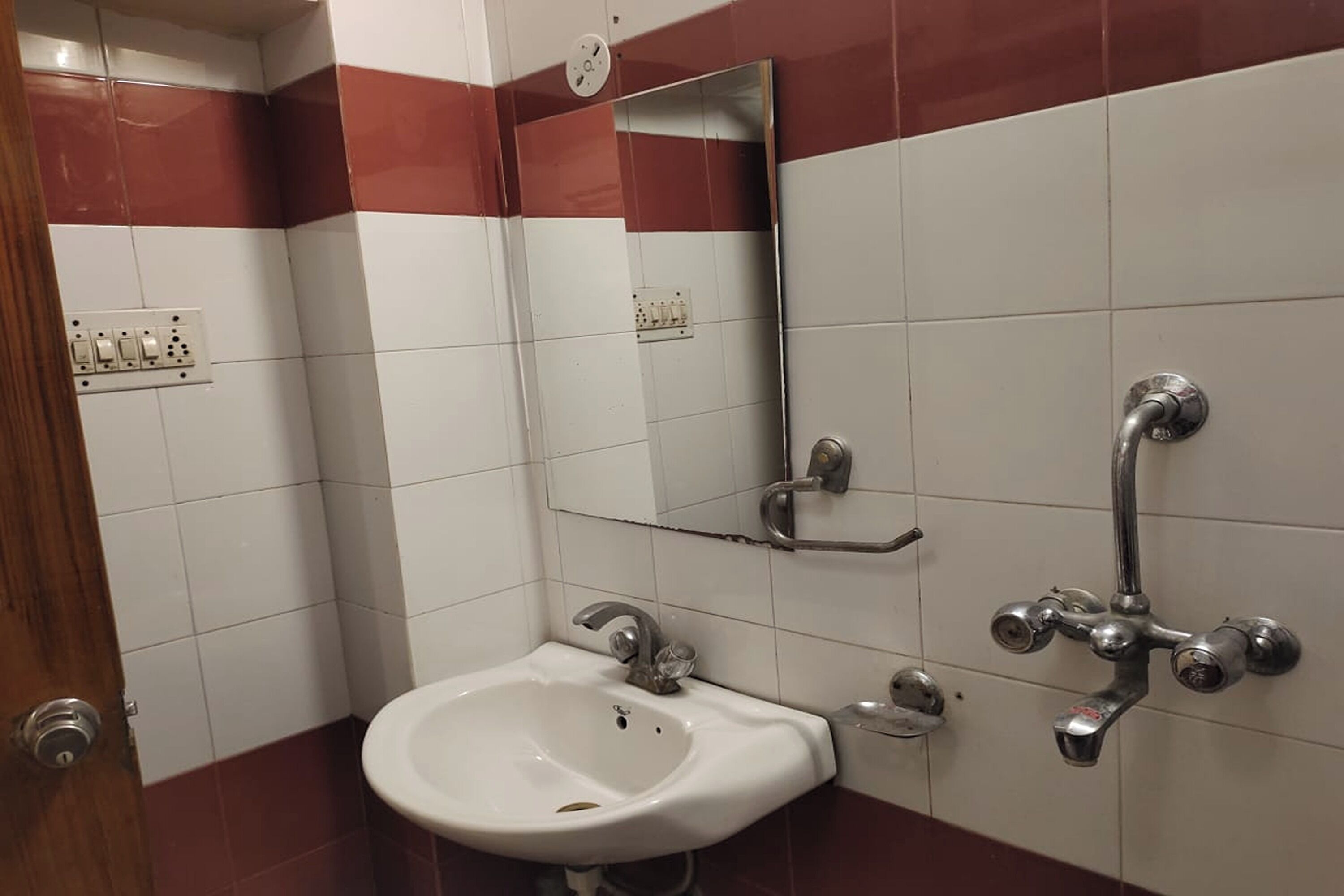 Un baño con lavamanos blanco, un espejo y una ducha con grifo cromado.