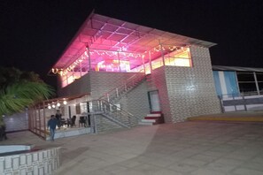 Un edificio con fachada de ladrillo, una escalera y un espacio exterior cubierto con guirnaldas de luces.