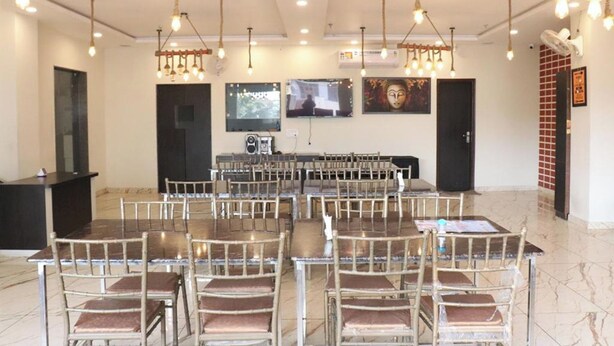 Un salón de conferencias con varias mesas y sillas, una pantalla de televisión y un sistema de sonido.