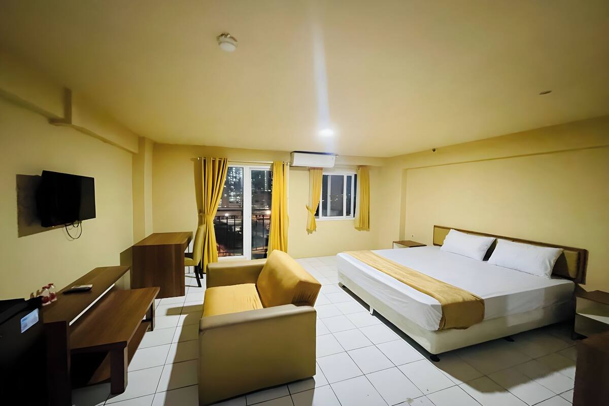 A hotel room with a bed, a sofa, a desk, and a television.
