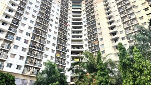 A high-rise residential building with multiple balconies, air conditioning units, and a dense arrangement of windows. - Hotel Riau (Bekasi)