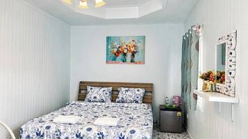Un dormitorio con cama, un cuadro, un espejo y una mesita con tetera.