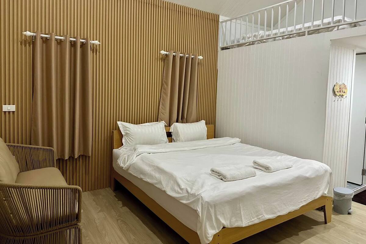 Une chambre à coucher avec un lit, une chaise, un panneau mural en bois et un plafond blanc.