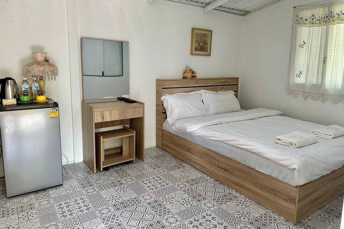 Une chambre avec un lit, un bureau, un réfrigérateur et un miroir.